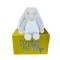 Blue and gray bunny rabbit stuffed animal with floppy ears sitting on a yellow box ready to be sent as a care package. send a PRAYER : sendaprayernow.com